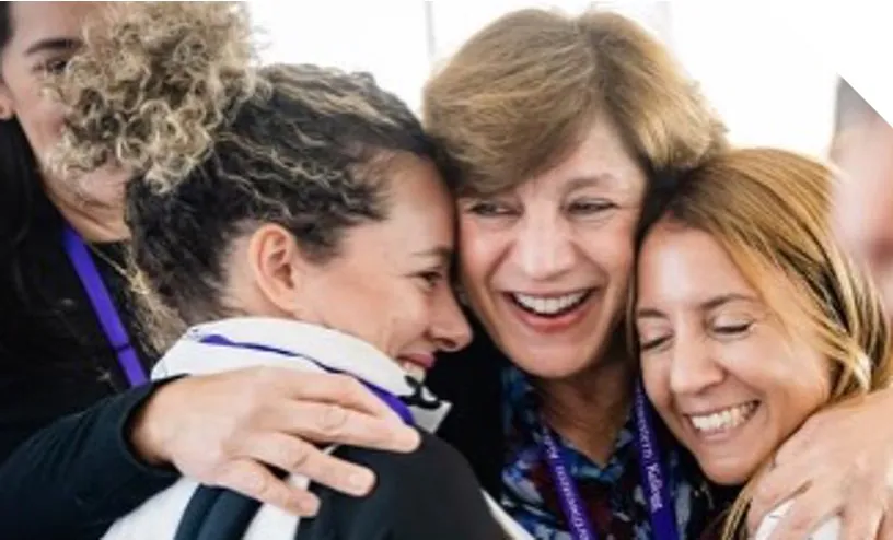Women@EMBA members embracing at a community event